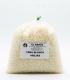 Bolsa transparente de un kilogramo llena de pequeñas perlas de cera blanca de abejas, con una etiqueta informativa al frente.